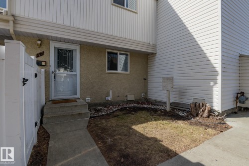 Inviting property entrance featuring a concrete walkway, a white fence, and a front door with a glass insert - 37 Woodvale Village, Edmonton, AB - Outdoor With Exterior