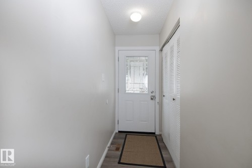 Entryway featuring light-colored walls, a white door with decorative glass inserts, and a closet with white louvered bifold doors - 37 Woodvale Village, Edmonton, AB - Indoor Photo Showing Other Room