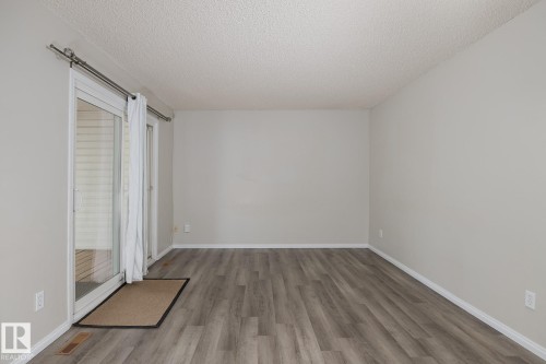 This room features light grey walls and grey wood-look flooring - 37 Woodvale Village, Edmonton, AB - Indoor Photo Showing Other Room