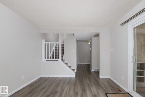 The property features light gray walls, a textured white ceiling, and wood-look flooring - 37 Woodvale Village, Edmonton, AB - Indoor Photo Showing Other Room