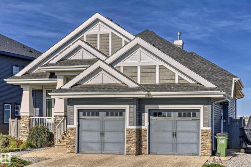The property features a dark gray shingled roof and siding, with white trim and stone accents on the facade - 3908 Ginsburg Crescent, Edmonton, AB - Outdoor With Facade