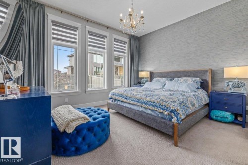 Bedroom featuring three large windows with blinds, a chandelier, and textured wallpaper - 3908 Ginsburg Crescent, Edmonton, AB - Indoor Photo Showing Bedroom