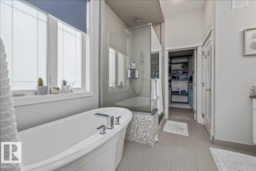 The property features a spacious bathroom with a freestanding bathtub, a walk-in shower with glass enclosure, and a well-organized closet - 3908 Ginsburg Crescent, Edmonton, AB - Indoor Photo Showing Bathroom
