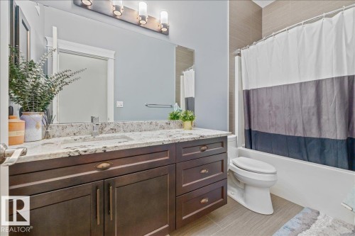 This bathroom features a spacious vanity with a granite countertop and a white sink - 3908 Ginsburg Crescent, Edmonton, AB - Indoor Photo Showing Bathroom