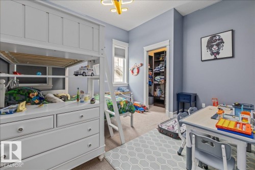 This room features light blue walls, a window with a white frame, and an open closet with built-in shelving - 3908 Ginsburg Crescent, Edmonton, AB - Indoor