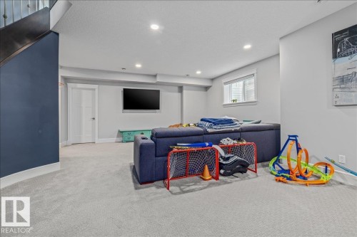 This versatile space features light-colored carpeting, recessed lighting, and a window with blinds - 3908 Ginsburg Crescent, Edmonton, AB - Indoor