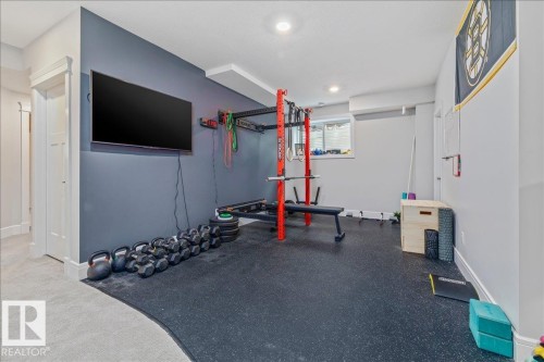 Dedicated space featuring a wall-mounted television, recessed lighting, and durable flooring, ideal for a home gym - 3908 Ginsburg Crescent, Edmonton, AB - Indoor