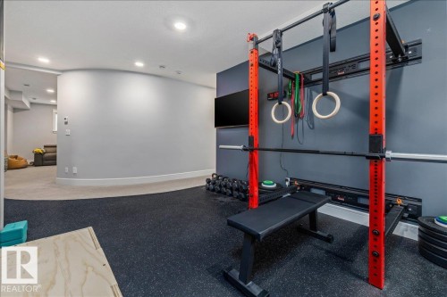 Dedicated fitness area featuring rubber flooring, a wall-mounted squat rack, and a curved wall design - 3908 Ginsburg Crescent, Edmonton, AB - Indoor