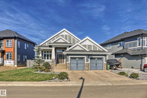 The property features a well-maintained front lawn and a paved driveway leading to a two-car garage - 3908 Ginsburg Crescent, Edmonton, AB - Outdoor With Facade