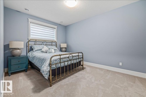 Well-appointed room featuring a window with blinds, light blue walls, and a light-colored carpet - 3908 Ginsburg Crescent, Edmonton, AB - Indoor Photo Showing Bedroom