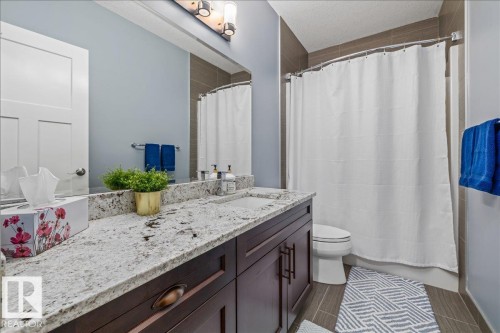 Bathroom featuring a vanity with a white granite countertop and dark wood cabinetry - 3908 Ginsburg Crescent, Edmonton, AB - Indoor Photo Showing Bathroom