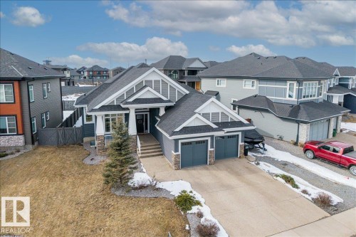 This property features a spacious two-car garage, a paved driveway, and a well-maintained lawn - 3908 Ginsburg Crescent, Edmonton, AB - Outdoor With Facade