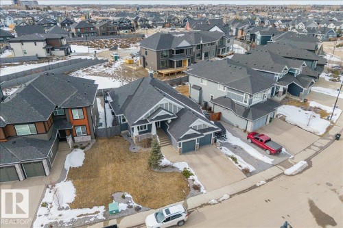 The property features a well-maintained lawn and a paved driveway leading to an integrated two-car garage - 3908 Ginsburg Crescent, Edmonton, AB - Outdoor