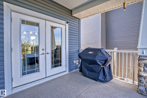 The property features a patio area with a textured floor, accessible through double glass doors - 3908 Ginsburg Crescent, Edmonton, AB - Outdoor With Deck Patio Veranda With Exterior