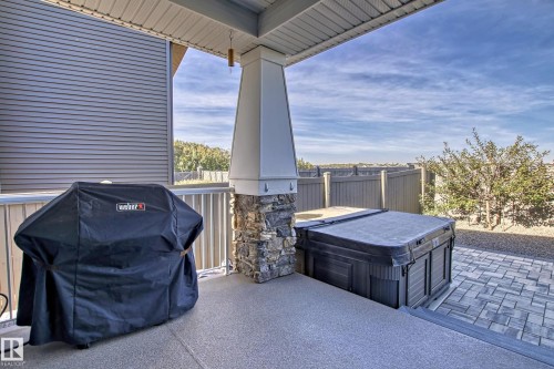 The property features a covered patio with a stone-accented column, offering a private outdoor space - 3908 Ginsburg Crescent, Edmonton, AB - Outdoor With Deck Patio Veranda With Exterior