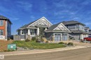 The property features a dark gray exterior with light gray and white trim, a stone facade, and an attached two-car garage - 3908 Ginsburg Crescent, Edmonton, AB  - Outdoor With Facade 