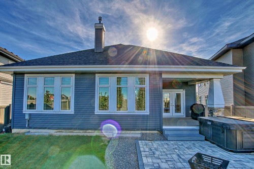 The property features a back exterior with blue siding, a dark shingle roof, and a prominent chimney - 3908 Ginsburg Crescent, Edmonton, AB - Outdoor With Deck Patio Veranda