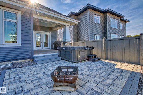 The property features a spacious patio with paver stones, a hot tub, and a privacy fence - 3908 Ginsburg Crescent, Edmonton, AB - Outdoor With Deck Patio Veranda