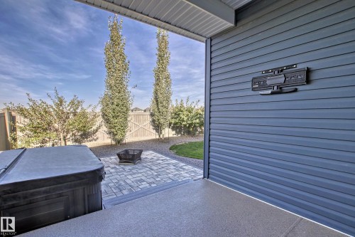 The property features a spacious paved patio area, a fire pit, and a hot tub - 3908 Ginsburg Crescent, Edmonton, AB - Outdoor With Exterior