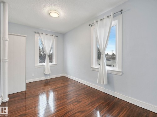 This room features rich, dark wood flooring, two windows with white trim, and a ceiling-mounted light fixture - 12141 96 Street, Edmonton, AB - Indoor Photo Showing Other Room