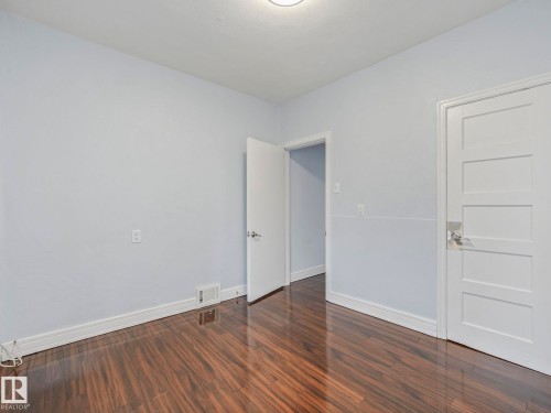 This room features dark wood flooring, light blue walls, white trim, and white doors - 12141 96 Street, Edmonton, AB - Indoor Photo Showing Other Room