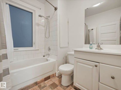 Bathroom featuring a white vanity with sink, a white bathtub with subway tile surround, and tiled flooring - 12141 96 Street, Edmonton, AB - Indoor Photo Showing Bathroom