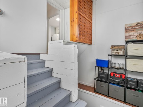 Stairway featuring painted wooden steps and white risers, with storage shelving visible to the right - 12141 96 Street, Edmonton, AB - Indoor