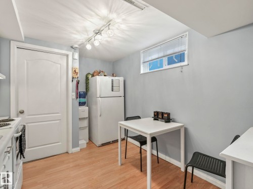The kitchen features light wood flooring, a white refrigerator, and a window with blinds - 12141 96 Street, Edmonton, AB - Indoor