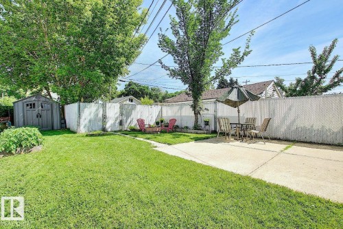 The property features a spacious yard with a lush lawn, a storage shed, and a paved patio area - 12141 96 Street, Edmonton, AB - Outdoor