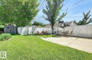 The property features a spacious yard with a lush lawn, a storage shed, and a paved patio area - 12141 96 Street, Edmonton, AB  - Outdoor 