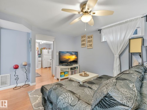 Living room featuring light blue walls, a ceiling fan with integrated lighting, and light-toned flooring - 12141 96 Street, Edmonton, AB - Indoor