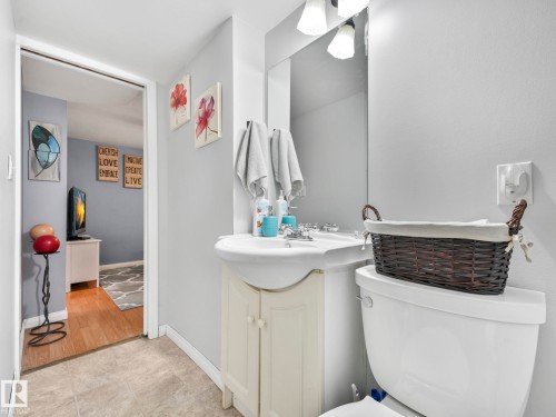 This bathroom features a white ceramic sink with a vanity cabinet, a wall-mounted mirror, and a toilet - 12141 96 Street, Edmonton, AB - Indoor Photo Showing Bathroom