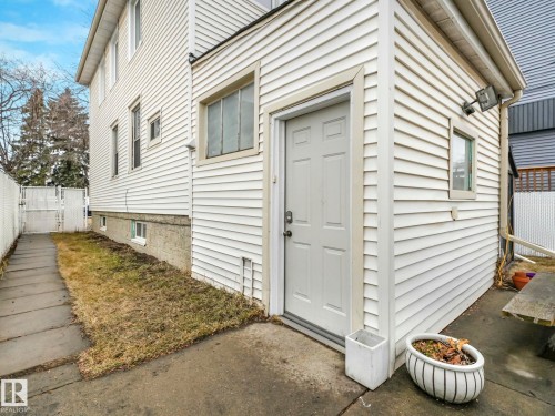 The property features white siding and a white door, with a paved pathway leading along the side - 12141 96 Street, Edmonton, AB - Outdoor With Exterior