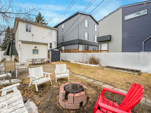 The property features a backyard with a concrete patio, a lawn area, and a brick fire pit - 12141 96 Street, Edmonton, AB - Outdoor With Deck Patio Veranda With Exterior