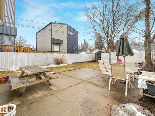 The property features a concrete patio area, a lawn, and a white chain-link fence - 12141 96 Street, Edmonton, AB - Outdoor