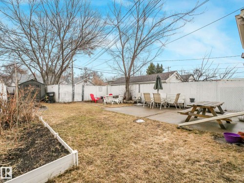 The property features a fenced yard with a concrete patio, a raised garden bed, and a storage shed - 12141 96 Street, Edmonton, AB - Outdoor