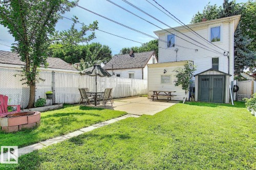 The property features a fenced yard with a lawn, a paved patio area, and a storage shed - 12141 96 Street, Edmonton, AB - Outdoor With Deck Patio Veranda