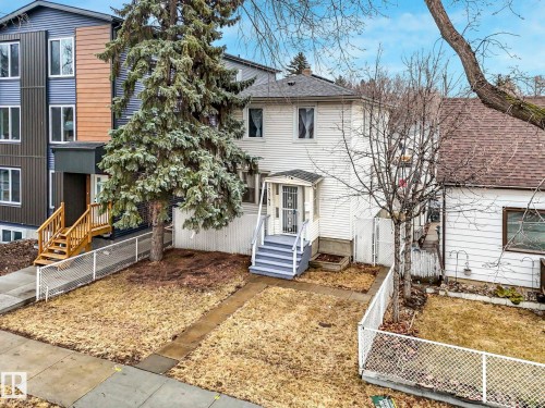 The property features a traditional white facade with a covered porch and front stairs - 12141 96 Street, Edmonton, AB - Outdoor