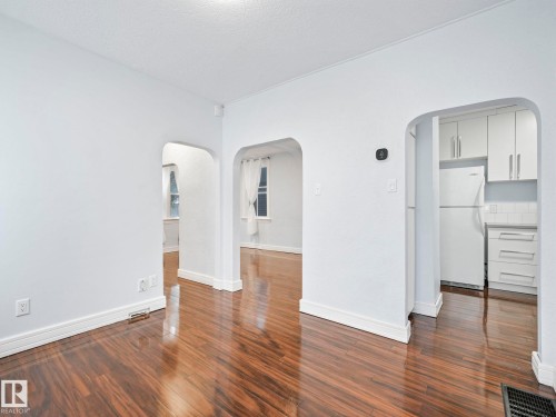 The interior features hardwood flooring, white walls, and arched doorways providing access to other areas of the property - 12141 96 Street, Edmonton, AB - Indoor