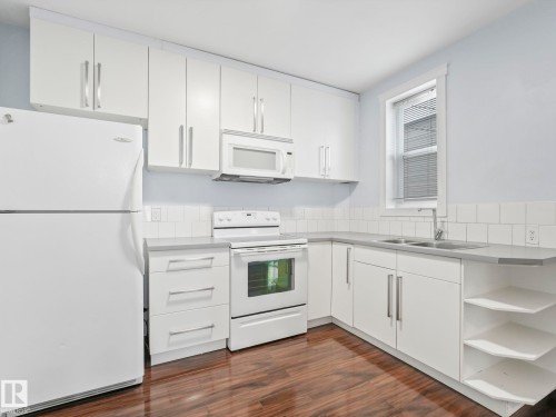 Kitchen featuring white cabinetry, appliances, and a double basin sink - 12141 96 Street, Edmonton, AB - Indoor Photo Showing Kitchen With Double Sink