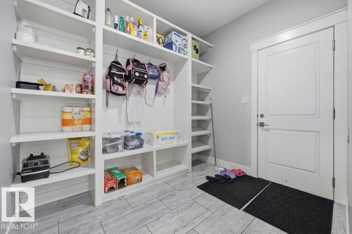 Mudroom featuring extensive white built-in shelving, a white door with a silver handle, and light-colored tile flooring - 17534 60A Street, Edmonton, AB - Indoor With Storage