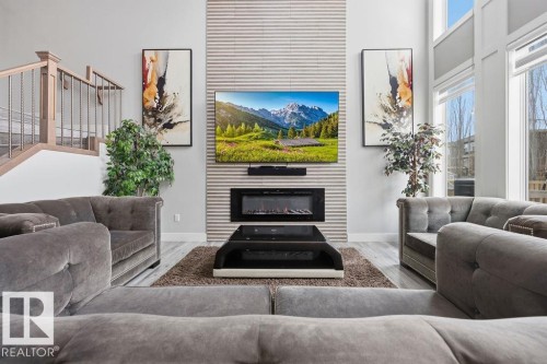 The living area features high ceilings, large windows, and light-colored flooring - 17534 60A Street, Edmonton, AB - Indoor Photo Showing Living Room With Fireplace