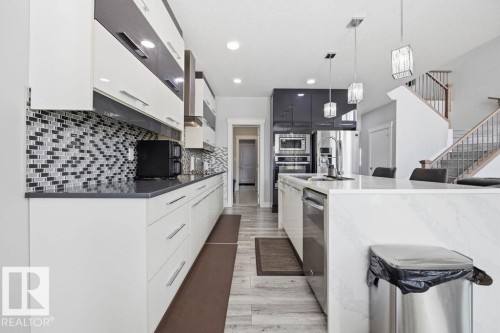 The kitchen features white cabinetry with polished chrome hardware, a patterned tile backsplash, and dark countertops - 17534 60A Street, Edmonton, AB - Indoor Photo Showing Kitchen With Upgraded Kitchen
