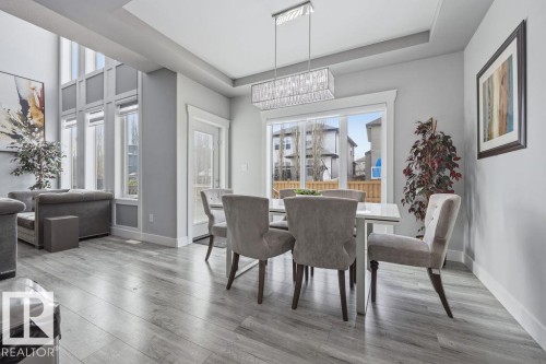 The open-concept living and dining area features high ceilings, extensive windows, and light wood-style flooring - 17534 60A Street, Edmonton, AB - Indoor Photo Showing Dining Room