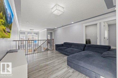 The property features a bright living area with light-toned flooring, a decorative ceiling light fixture, and crown molding - 17534 60A Street, Edmonton, AB - Indoor