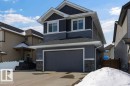 The property features a two-story exterior with dark grey and light grey siding, a front-facing garage with a dark grey door, and stone accents on the lower facade - 17534 60A Street, Edmonton, AB  - Outdoor 