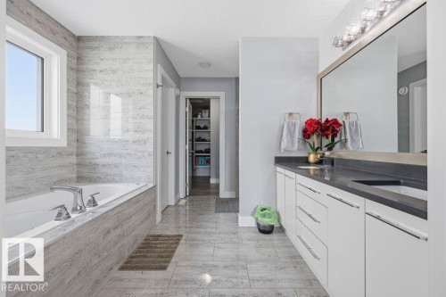 Bathroom featuring a large vanity with dual sinks, a spacious bathtub with tile surround, and tile flooring - 17534 60A Street, Edmonton, AB - Indoor Photo Showing Bathroom