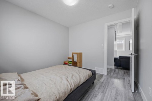 This bright room features light grey walls, a ceiling light fixture, and grey wood-style flooring - 17534 60A Street, Edmonton, AB - Indoor Photo Showing Bedroom