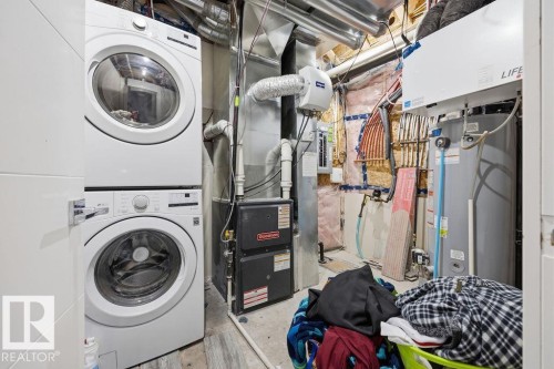 This utility area features a stacked washer and dryer, a water heater, and a furnace - 17534 60A Street, Edmonton, AB - Indoor Photo Showing Laundry Room