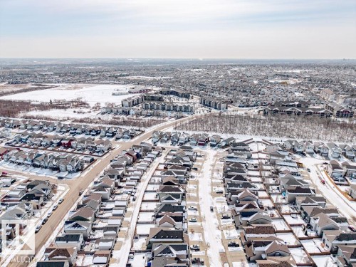 Aerial view showcasing the residential area with snow-covered roofs and streets, surrounded by open, snow-covered land and wooded areas - 17534 60A Street, Edmonton, AB - Outdoor With View